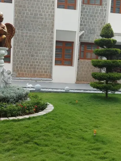 A closer view of the institutional landscape, highlighting a central statue and a spiral topiary tree. These elements serve as focal points in the formal garden design.