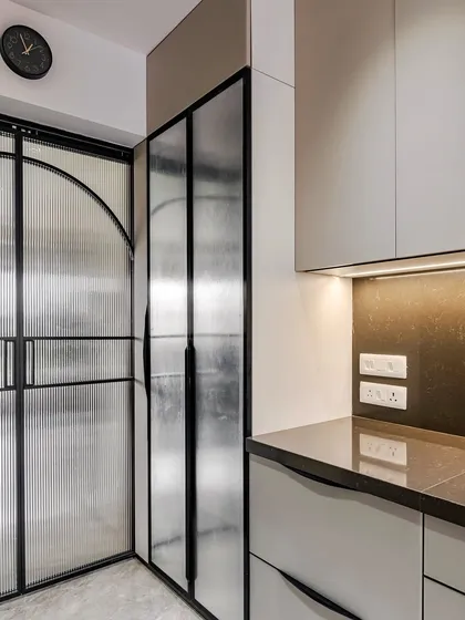 A corner view showing the fluted glass pantry door and the sleek cabinetry at our Kandivali project.