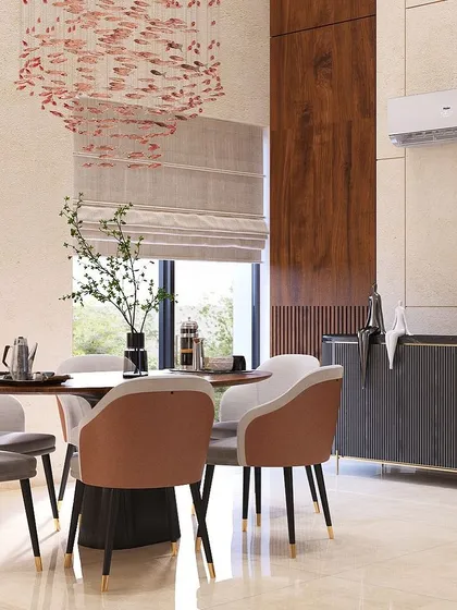 This double-height dining space in Nirvana Country feels grand and airy. The stunning chandelier acts as a centerpiece, while the round table and two-toned chairs create a sophisticated setting for meals.