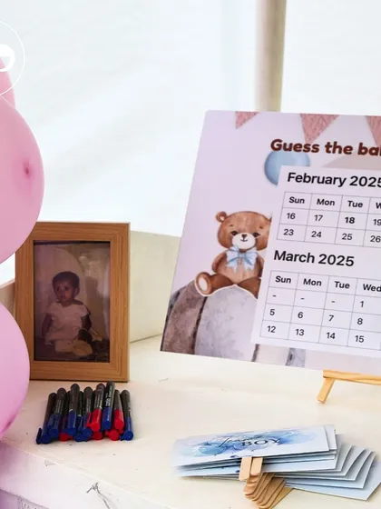A personalization table with a 'Guess the Baby's Birthday' calendar and childhood photos, creating a fun and engaging corner for guests.