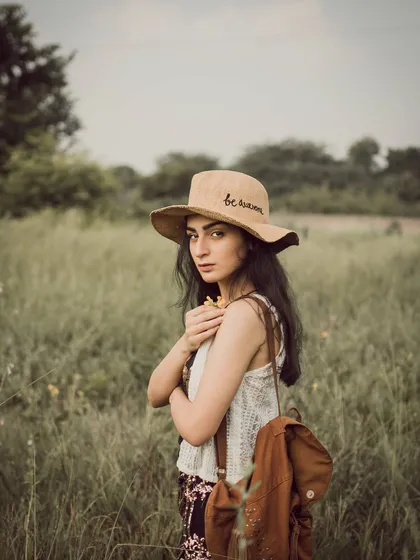 A quiet moment captured in a grassy field for a vintage-style portrait. This kind of shoot is perfect for capturing a pensive, natural mood using soft light and earthy tones.
