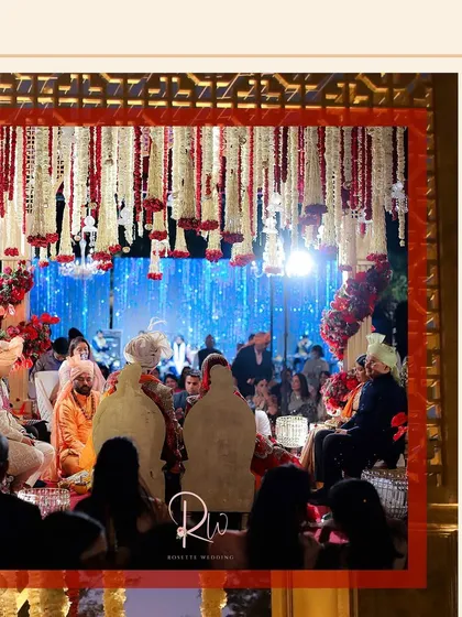 A shot from within the mandap during the ceremony, showing the couple surrounded by family under the breathtaking floral installation.