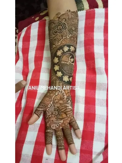 This design covers the full hand and part of the arm with traditional patterns. It features a large circular motif filled with fine lines and surrounded by floral and leaf elements.