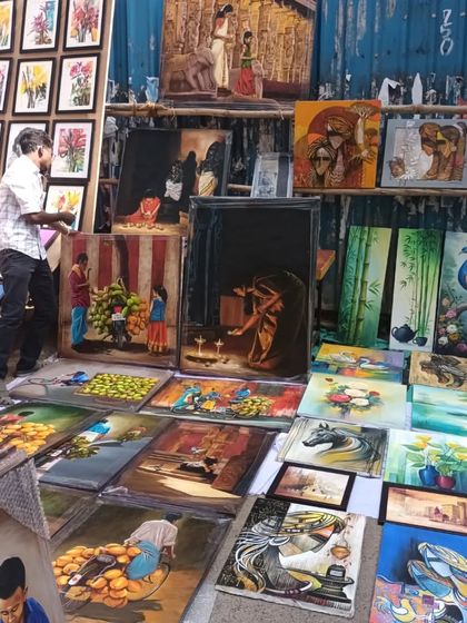 A wide view of an artist's stall at Chithrasanthe, showcasing a huge variety of paintings, from traditional to contemporary.
