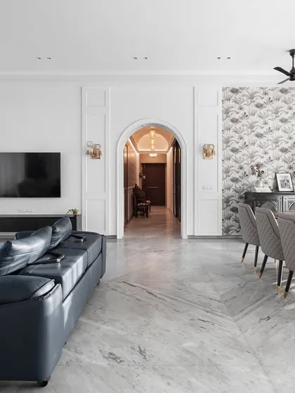 This expansive living and dining area is a perfect example of modern luxury. We used a foundation of white marble flooring and classic wall mouldings, then layered in a deep blue leather sofa and elegant chandeliers to create a space that feels both grand and welcoming.