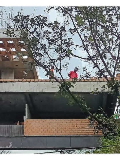 Workers on the terrace of the 'AGA' project, with the filler slab and exposed brickwork visible.