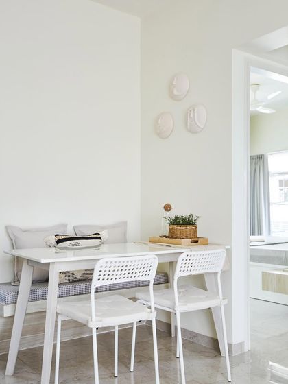 The dining area is a warm haven for family gatherings. A simple white table is paired with a bench and chairs, while unique wall fixtures add a touch of personality to the minimalist space.