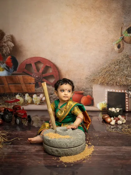 Here, she is using a traditional stone grinder prop, adding a touch of authenticity to this Maharashtrian themed baby shoot.