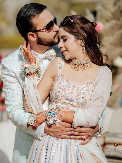 A close, affectionate portrait of the couple at their Mehendi, with the groom's tender kiss on the bride's forehead.