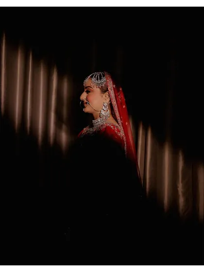An artistic bridal portrait using strong directional light to create a dramatic play of light and shadow. This technique highlights the bride's profile and creates a moody, cinematic feel.