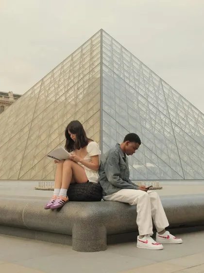 A powerful image of two models back-to-back in front of the Louvre pyramid, showcasing their custom kicks.