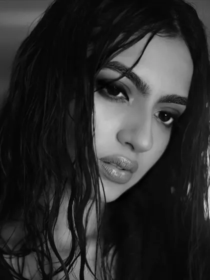 This monochrome portrait of Kashika Kapoor showcases an edgy, high-fashion aesthetic. The dramatic, dark smokey eye and glossy lips, combined with a wet hair look, create a powerful and intense editorial style.