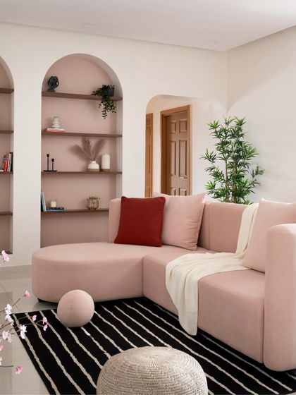 The custom-designed curved sectional sofa is the star of this living room. Paired with a black and white striped rug and soft, round poufs, it emphasizes the home's theme of graceful curves and soft forms.