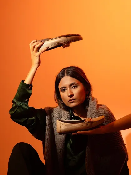 An unconventional pose for a footwear campaign. The model's direct gaze and the creative placement of the loafers create an edgy, high-fashion image that is more memorable than a standard shoe photo.