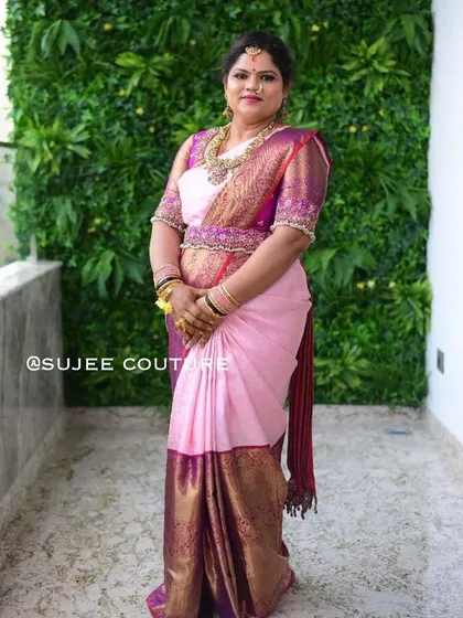 A client dressed in a beautiful pink and purple Kanchipuram silk saree. I designed the matching puff-sleeve blouse with an embroidered border to complete her traditional look.