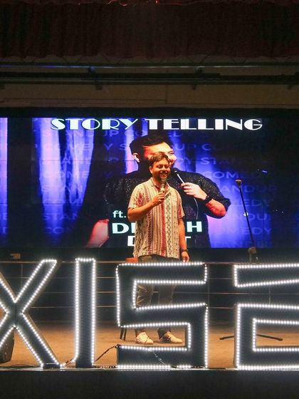 Devesh Dixit on stage for a storytelling and comedy session at Axis, VNIT Nagpur, with custom LED branding.
