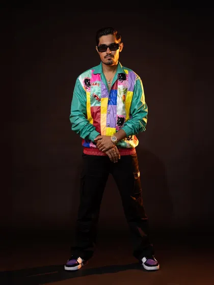 This full-length shot shows the complete look for Amit. The colorful jacket, black cargo pants, and stylish sneakers create a cool, contemporary, and approachable vibe.