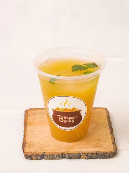 A refreshing glass of aam panna or a similar mango drink, branded for 'Biryani Bowls'. The clean, simple shot is perfect for adding a beverage to a delivery menu.