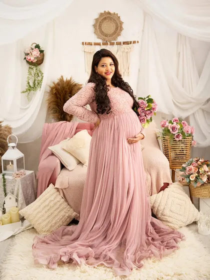 A joyful and confident pose. The mother-to-be stands in the center of the pink boho setup, her smile radiating happiness and anticipation.