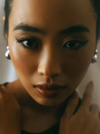 An intimate, film-like close-up portrait. The warm tones, soft focus, and the texture from shooting through a prop create a nostalgic and gentle mood.