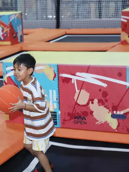 A young basketball player in action on the trampoline court. The springy surface gives every kid the chance to feel like a pro as they go for a slam dunk.