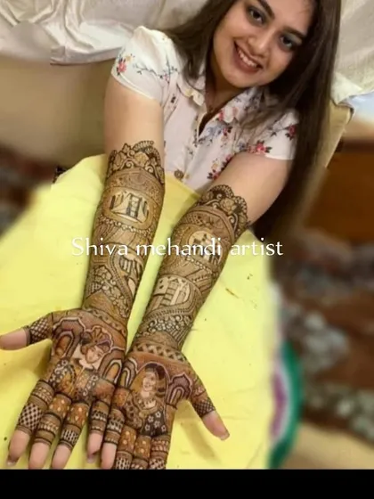A happy bride showcasing her personalized mehendi, which includes portraits of her and her partner. The design captures their likeness and is surrounded by intricate wedding story elements.