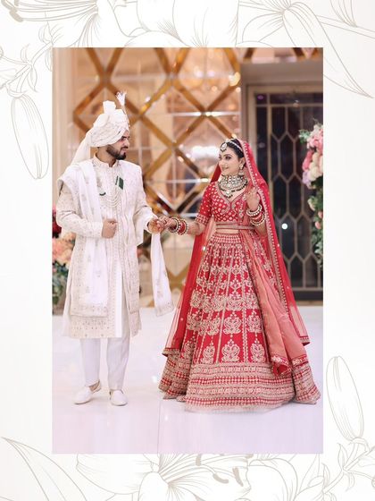 A classic couple walking shot. The bride's red lehenga and the groom's white sherwani create a beautiful contrast.