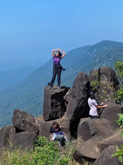 Trekkers climbing and posing on the interesting rock formations near Kurinjal peak.