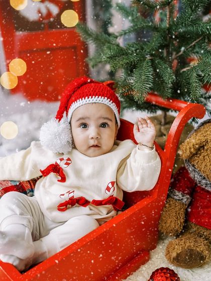 This little model was a pro. A baby girl in a red sleigh, waving to the camera during her Christmas mini-session.