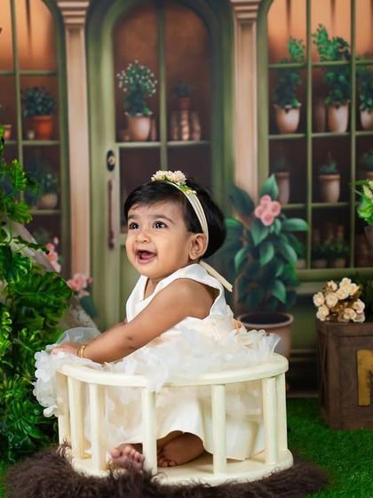 A happy toddler in an aesthetic, garden-themed set, complete with a miniature teepee and "ONE" blocks.