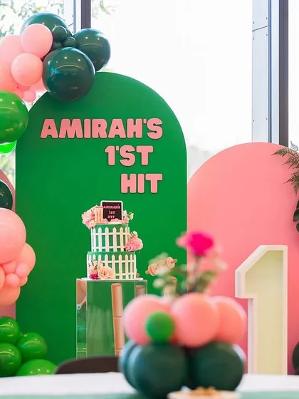 A detail shot of the cricket-themed cake and the "Amirah's 1st Hit" backdrop, showing the unique and personalized concept for this sporty celebration.