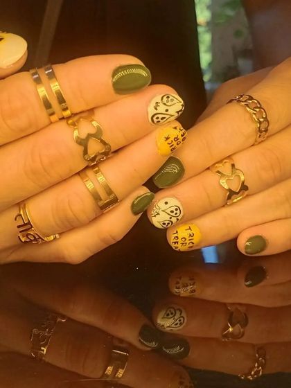 A fun and spooky Halloween-themed manicure with ghosts, leopard print, and "trick or treat" lettering.