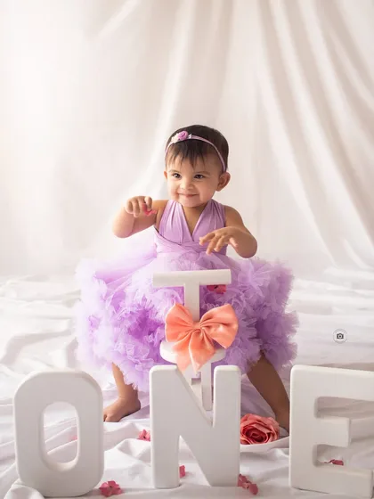 Ready to ride into year two. A happy birthday girl with her tricycle and "ONE" letters.