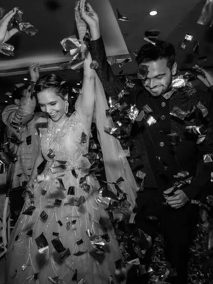 A classic black and white shot of the couple's entrance. The confetti shower and their happy expressions make for a timeless and celebratory photograph.