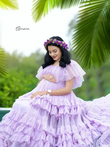 A beautiful portrait of a mother-to-be in a lavender ruffled gown, wearing a floral crown. The palm trees in the background give a tropical feel to the shoot.
