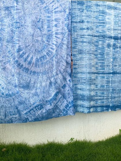 Two different indigo tie-dye patterns drying side-by-side. Each one has its own unique character, showcasing the versatility of the shibori technique.
