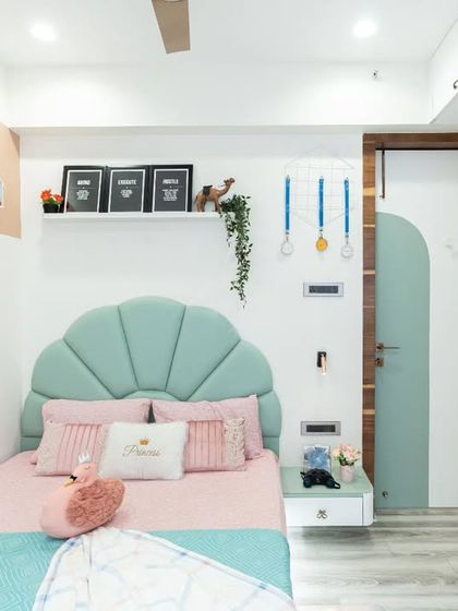 The wall decor, including the floating shelf with framed quotes and the house-shaped nooks, adds personality and provides space for the child's favorite things.