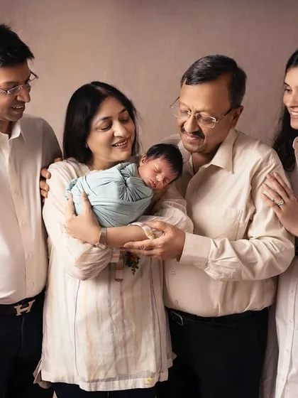The whole family gathered together, their gazes drawn to the tiny new baby. I used soft, neutral tones in their clothing and the backdrop to keep the focus on their connection.