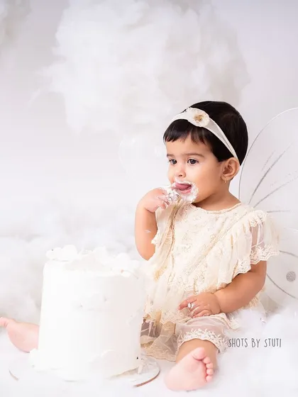 A final, sweet lick of frosting from her fingers. These are the moments that perfectly capture the essence of a first birthday cake smash.