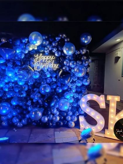 A stunning blue-lit balloon wall with a 'Happy Birthday' neon sign and marquee letters, creating a cool, club-like atmosphere.