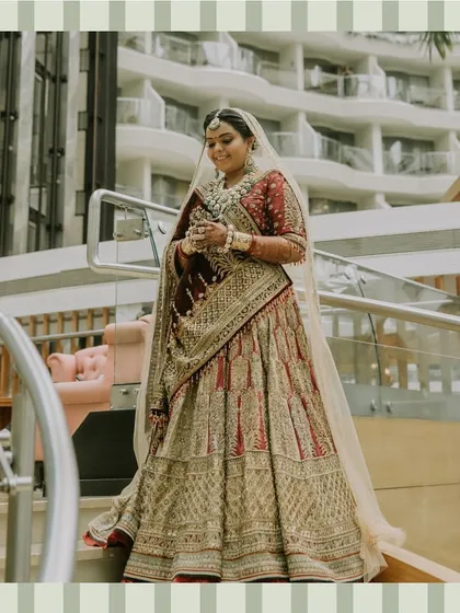 A full-length portrait of the bride, looking absolutely radiant and regal in her richly embroidered wedding lehenga.