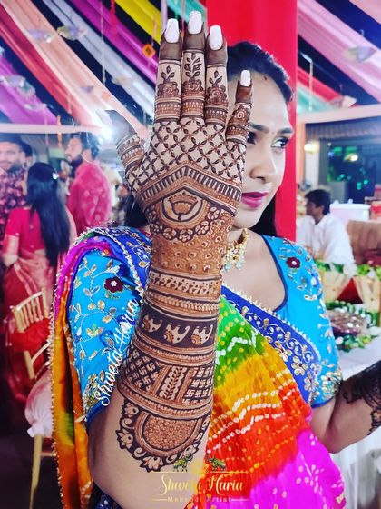 A full and detailed back-hand design for the groom's sister, featuring bands of baby elephants and lotus motifs.