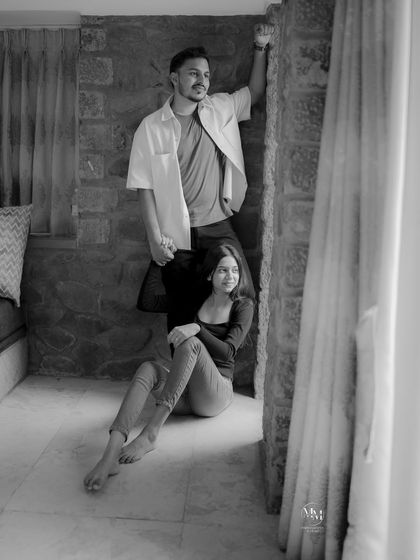 A candid black and white photo by the window. Their relaxed poses and the natural light create a soft and intimate atmosphere.