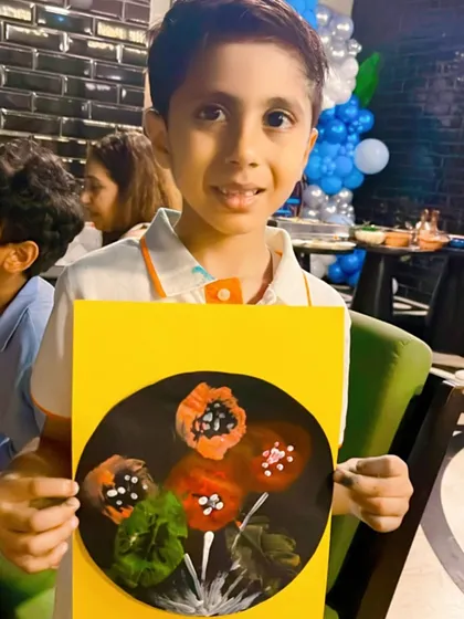 The proud smile of a young artist holding up his finished bubble wrap and Q-tip painting. My goal is to make every child feel a sense of accomplishment and joy in their own creativity.