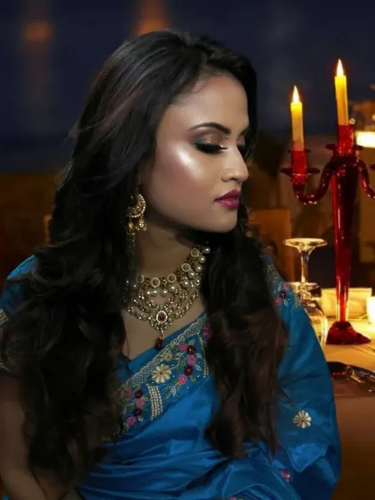 A romantic, candle-lit photoshoot look. The client is wearing a blue saree with soft, glowing makeup.