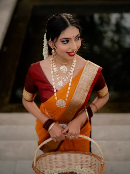 A classic portrait of a model in a traditional saree, holding a basket of flowers. The soft lighting and gentle smile create a warm and inviting image.