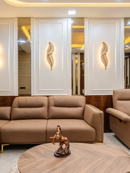A closer look at the living area in Mahad, focusing on the comfortable sectional sofa with a built-in recliner. The wall paneling with integrated lighting adds a layer of sophistication and warmth.