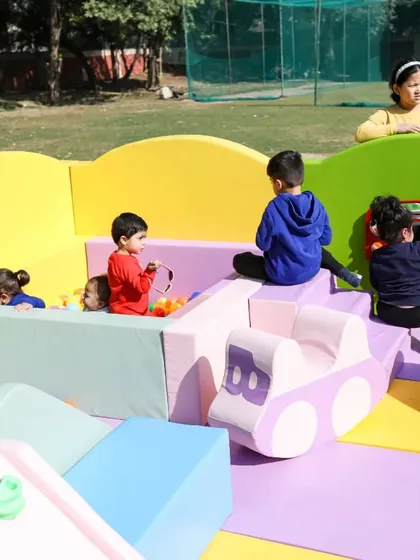Kids enjoying various elements of the soft play zone, from the ball pit to the soft car rocker.