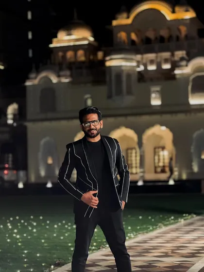 Ready for the hustle in Jaipur. A sharp, black pinstripe suit for a sophisticated evening event against the backdrop of a beautifully lit palace.