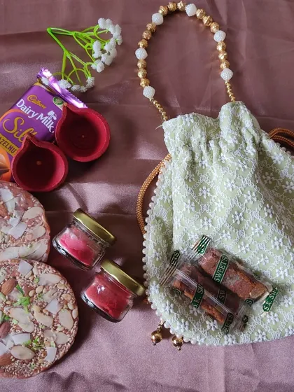 Celebrate the festival of lights with a traditional yet modern Diwali gift set. This hamper includes a beautiful potli bag, hand-painted diyas, scented candles, dry fruit chikki, and Dairy Milk Silk for a sweet touch.